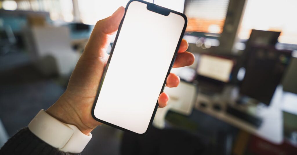 Hand holding smartphone empty screen mockup office interior