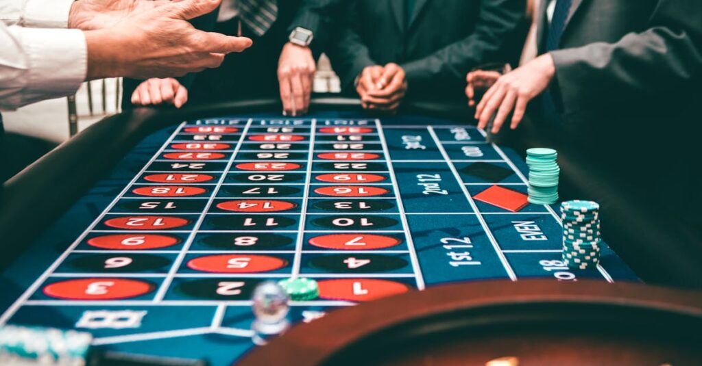 Group of people playing roulette, placing bets in a casino setting.